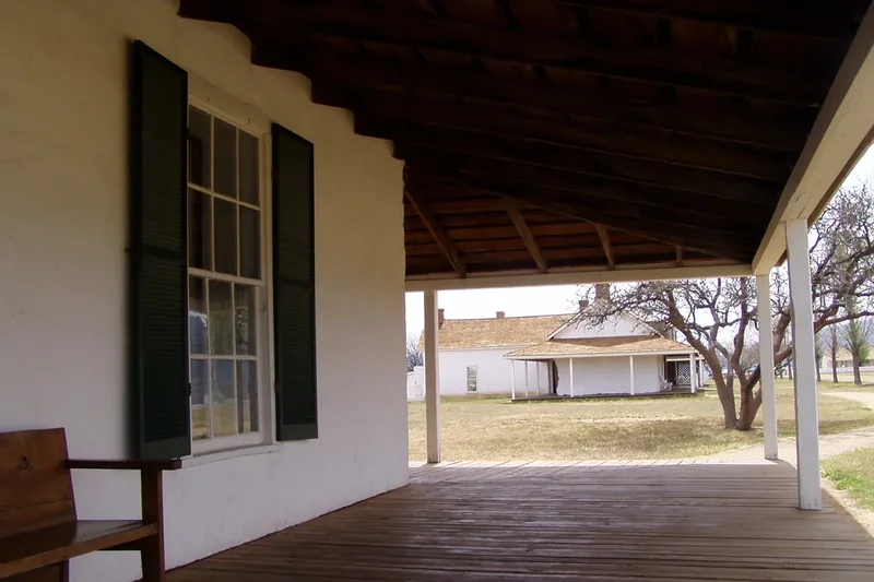 A whitewashed officers’ quarters with a shaded wooden porch at Fort Verde State Historic Park