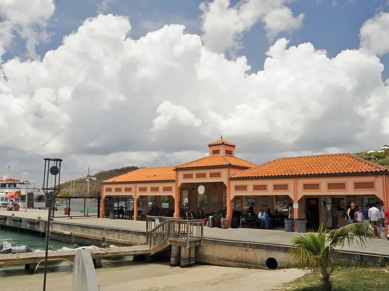 The ferry terminal at Cruz Bay, a long building with red tile roofs on the waterfront, with boats and people on the dock