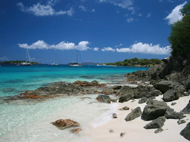 Salomon Bay seen from Honeymoon Beach, turquoise water, white sand and boats moored off a rocky point