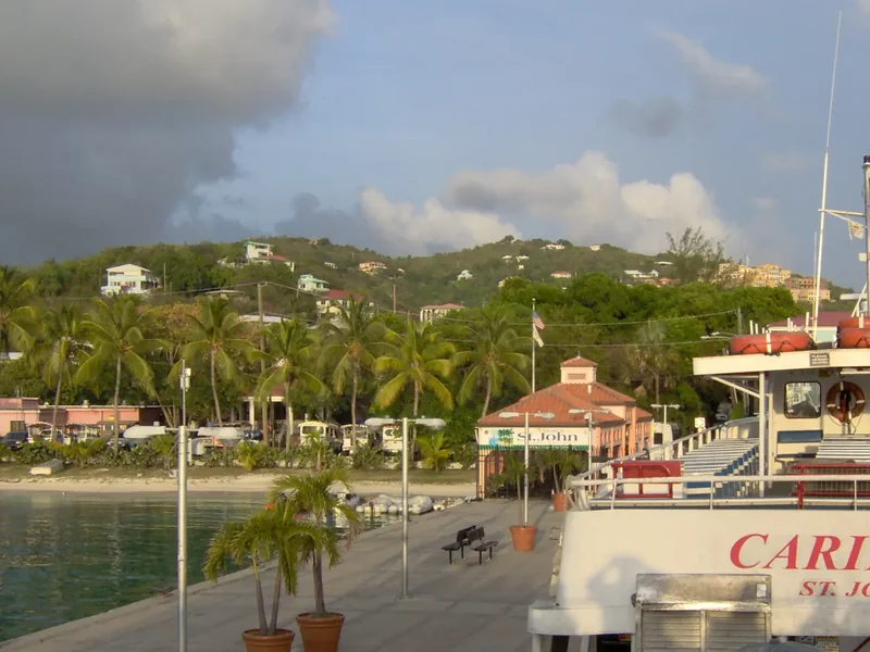 The landing pier at Cruz Bay with a ferry, palms and buildings on the hillside