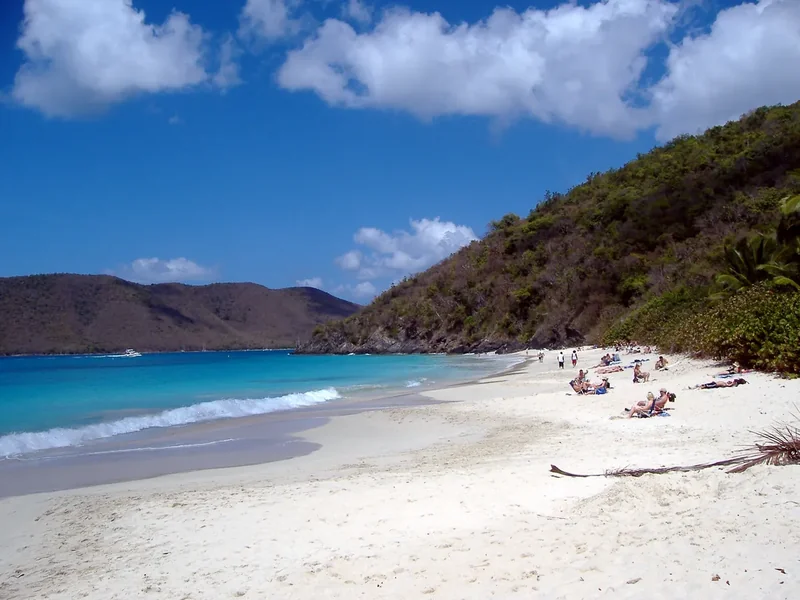 The long white-sand beach at Cinnamon Bay below steep green hills
