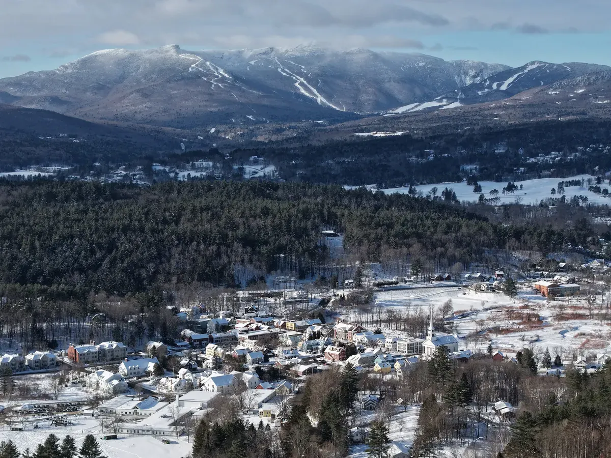Stowe village and the valley covered in snow, with a mountain range behind under a cloudy sky
