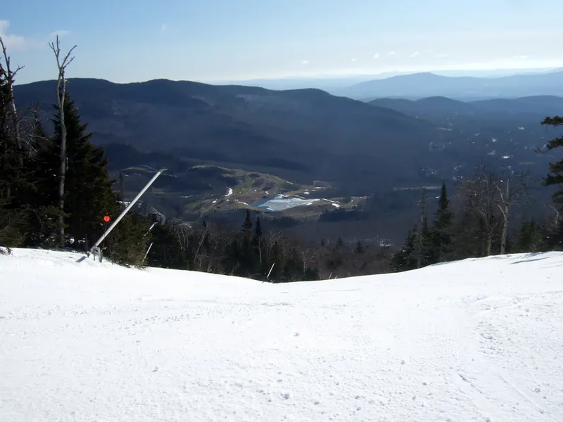 A groomed ski run at Stowe looking out over a valley of forested hills