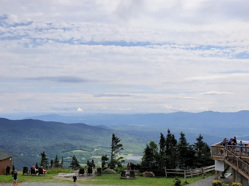 The view from the top of the mountain at Stowe over layers of hills, with people on a terrace