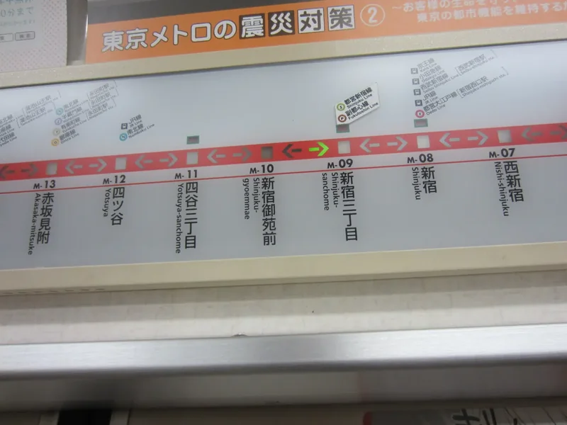 A Tokyo Metro line map above a train door, with station names in Japanese and English