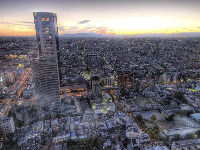 Sunset over Shinjuku from high above, towers and city lights spreading toward the horizon