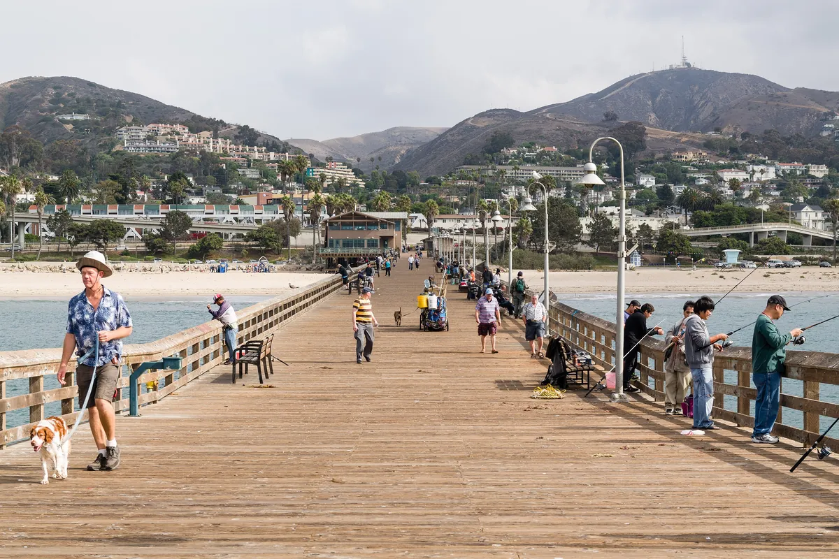 People fishing along the rail of the long wooden Ventura Pier over the Pacific on a clear day