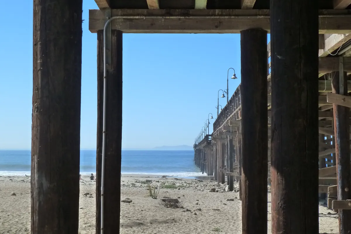Looking out under the wooden Ventura Pier from the promenade toward Santa Rosa Island on the horizon