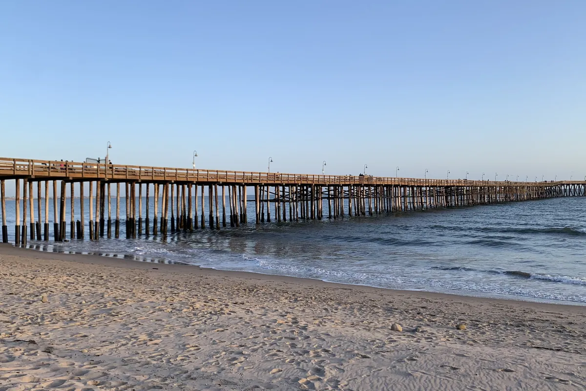 The Ventura Pier stretching out to sea under an orange sunset sky