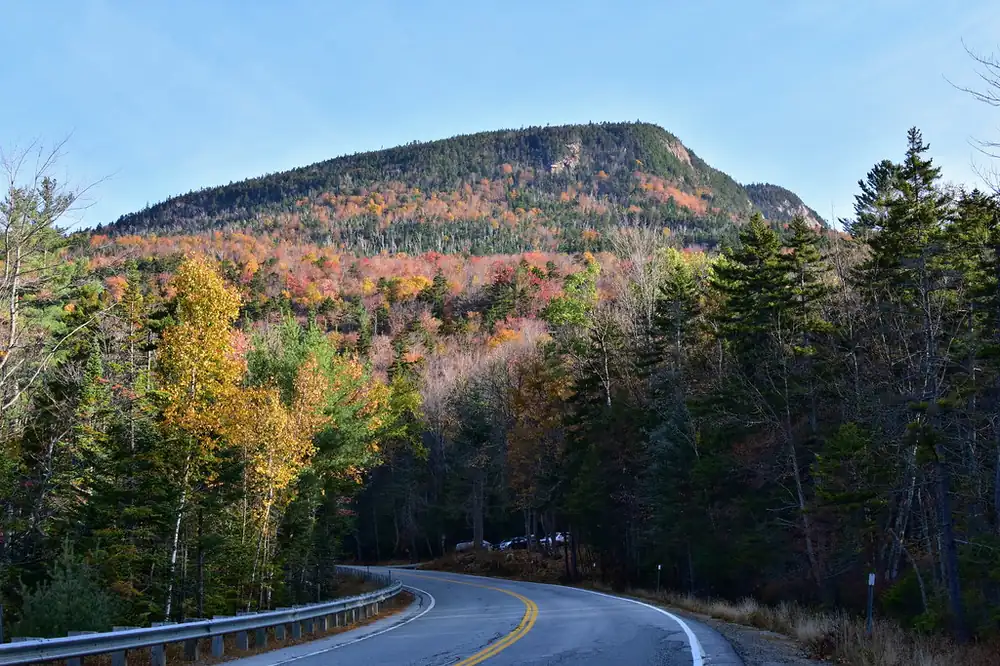 The Kancamagus Highway winding beneath a mountainside of fall color