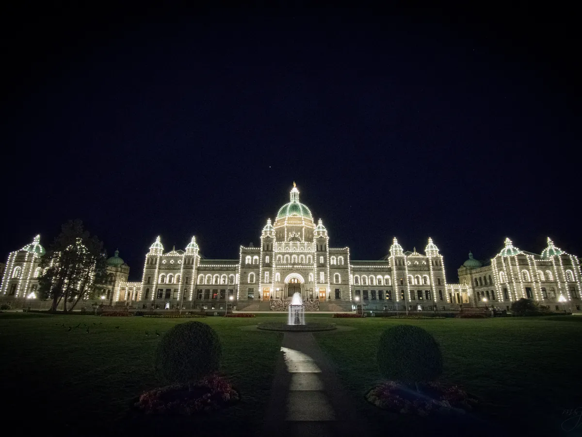 The BC Parliament Buildings outlined in white lights at night in Victoria