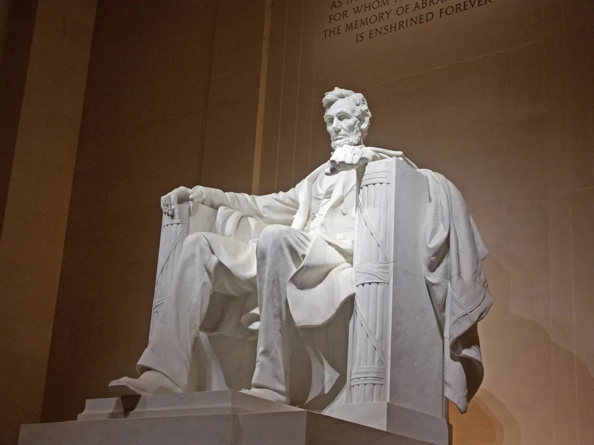 The seated statue of Abraham Lincoln inside the Lincoln Memorial, lit at night
