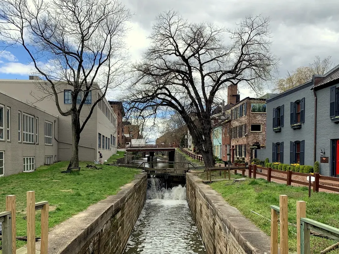 The C&O Canal in Georgetown with a stone lock, brick houses and bare trees along the towpath