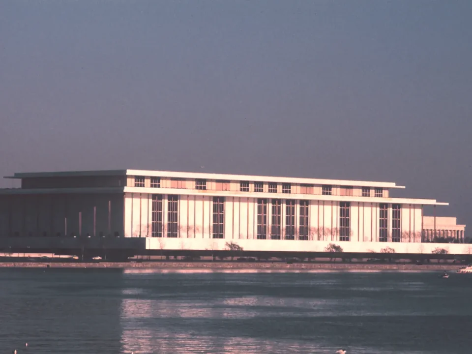 The Kennedy Center lit in late afternoon light, seen across the Potomac River