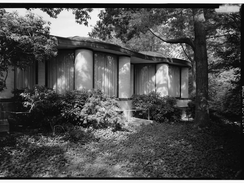 A garden view of a glass pavilion at Dumbarton Oaks among trees, in black and white