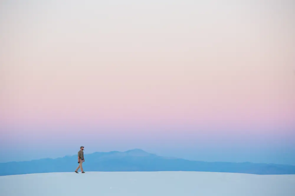 A lone hiker crossing white dunes